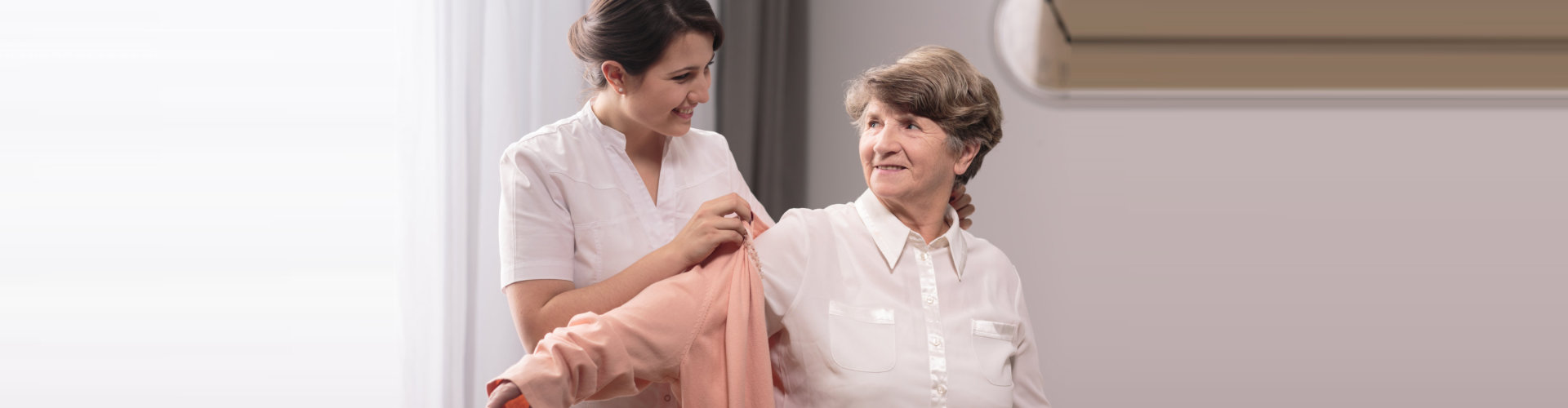 caregiver assisting elder woman on wearing a polo shirt concept